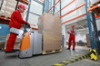 Photo: two workers working in storehouse with forklift loader two workers working in storehouse with forklift loader