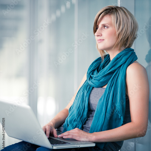 Photo: Pretty young female student with a laptop computer on college Pretty young female student with a laptop computer on college