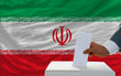 man voting on elections in iran in front of flag
