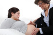 Doctor feeling a woman's pregnant stomach