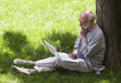 senior man working on a computer under a tree