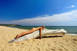 Beautiful young woman sunbathing on dry tree at wild beach