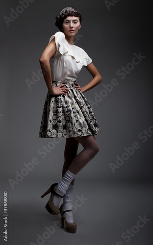 Photo: Graceful young woman posing on podium in retro clothes Graceful young woman posing on podium in retro clothes