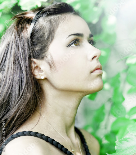Photo: Portrait of beautiful cute young girl yearning in leafage outdoo Portrait of beautiful cute young girl yearning in leafage outdoo