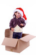 petite fille debout dans un carton avec chapeau de noel