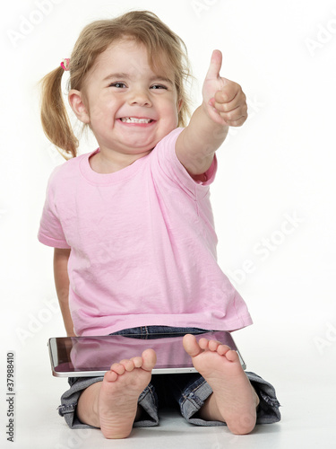 Photo: Adorable little girl on the floor playing with touchpad Adorable little girl on the floor playing with touchpad