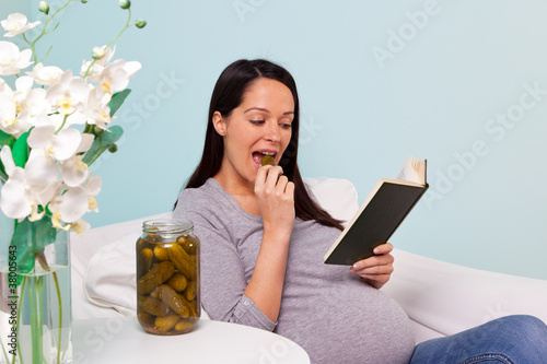 Photo: Pregnant woman eating a pickled gherkin. Pregnant woman eating a pickled gherkin.