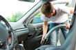 Man is hoovering or cleaning the car