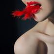 Foto: Young woman with feather in her mouth Young woman with feather in her mouth