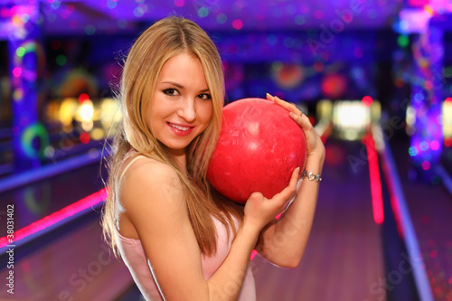 Photo: blonde girl stands and hugs red ball in bowling club blonde girl stands and hugs red ball in bowling club