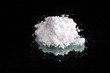 Cocaine drugs heap on a black mirror, close up view