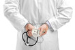 Studio shot of a doctor with dollar banknotes and handcuffs