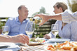Man pouring wine at sunny table