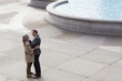 Couple hugging face to face near urban fountain