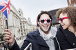 Foto: Portrait of exuberant couple with British flag and sunglasses riding double decker bus Portrait of exuberant couple with British flag and sunglasses riding double decker bus