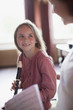 Grandmother with sheet music watching granddaughter practice on recorder