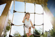 Portrait of smiling girl climbing rope at sunny playground