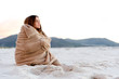 Beautiful woman covers herself on a cold beach