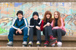 Group of happy teenagers sitting on the street in roller skate