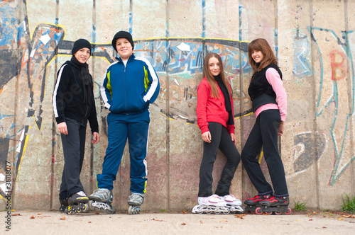 Photo: Group of teenagers going roller skating on cloudy autumn day Group of teenagers going roller skating on cloudy autumn day