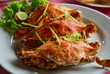 three large red crabs with salad and lime