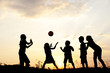 Silhouette, group of happy children playing on meadow,