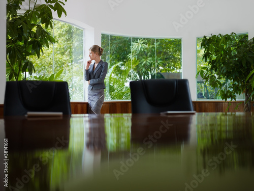 Foto: businesswoman contemplating out of window in meeting room businesswoman contemplating out of window in meeting room
