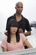Asian woman sitting on chair with hairstylist standing behind