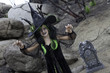 Girl in witch attire trying to scare you while standing in cemetery
