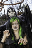 Photo: Little witch holding lantern with person costumed as grim reaper standing in background Little witch holding lantern with person costumed as grim reaper standing in background