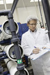 Man writing in clipboard while standing in bottling factory