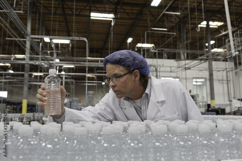 Photo: Quality control worker checking bottled water at bottling plant Quality control worker checking bottled water at bottling plant