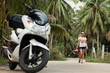 Young woman walking to her motorbike in tropical environment