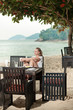Young woman having a coffee in outdoor ocean view restaurant