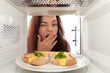 Girl looks in a microwave