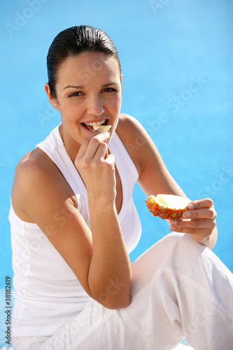 Photo: Woman eating bread at a poolside Woman eating bread at a poolside