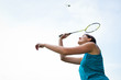 Pretty, young woman playing badminton in a city park