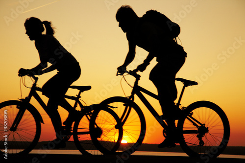 Foto: Young couple riding bicycles at sunset Young couple riding bicycles at sunset