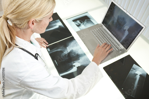Photo: Female Woman Hospital Doctor Looking at X-Rays & Laptop Female Woman Hospital Doctor Looking at X-Rays & Laptop