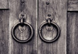 ancient wooden gate with door knocker rings