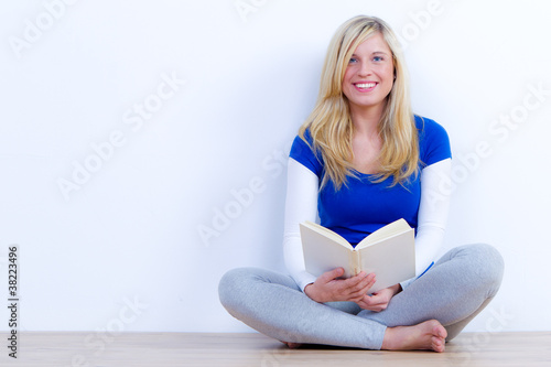 Foto: hübsche studentin sitzt mit einem buch auf dem boden hübsche studentin sitzt mit einem buch auf dem boden