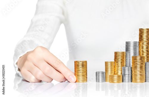 Photo: Hand adding a stack of coins to savings Hand adding a stack of coins to savings