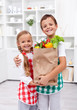 Happy healthy kids with the grocery bag in the kitchen Happy healthy kids with the grocery bag in the kitchen