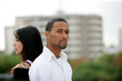 Young couple standing back-to-back on the outskirts of a city