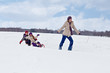 Children sleigh riding - their mother helping
