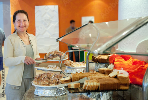 Photo: Mature woman chooses sweet pastry Mature woman chooses sweet pastry
