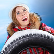 Foto: Laughing young pretty woman with a snowy winter tyre Laughing young pretty woman with a snowy winter tyre