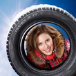 Foto: Beautiful woman looking through a snowy winter tyre Beautiful woman looking through a snowy winter tyre
