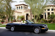 Luxurious convertible car parked in front of a mansion house