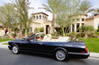 Black convertible car parked in front f luxury house